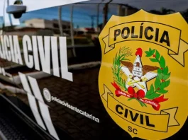 Porta do carro da Polícia Civil da Delegacia de Tijucas, com o logo da instituição visível.