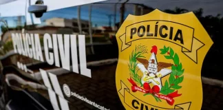 Porta do carro da Polícia Civil da Delegacia de Tijucas, com o logo da instituição visível.