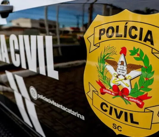 Porta do carro da Polícia Civil da Delegacia de Tijucas, com o logo da instituição visível.
