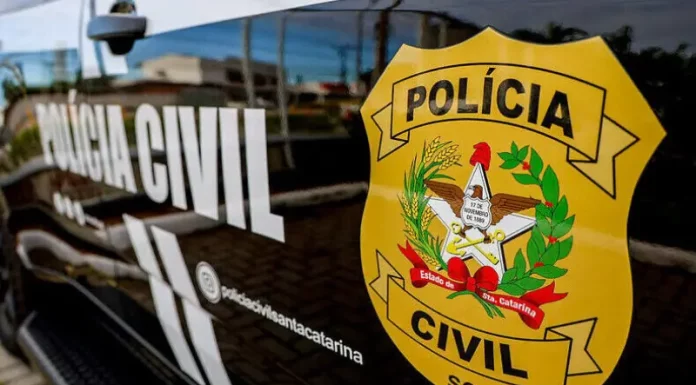 Porta do carro da Polícia Civil da Delegacia de Tijucas, com o logo da instituição visível.