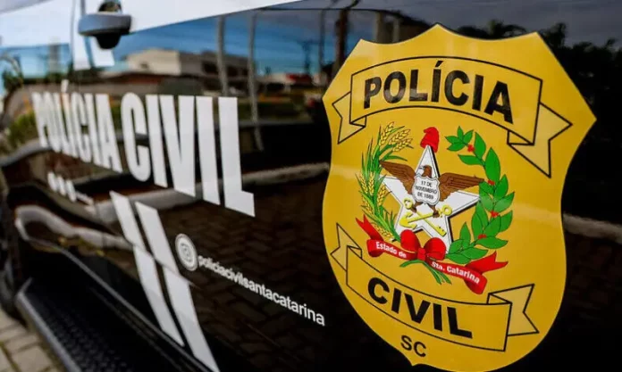 Porta do carro da Polícia Civil da Delegacia de Tijucas, com o logo da instituição visível.