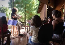 Crianças aprendendo a tocar violino durante oficina do Festival Multicultural na Guarda do Embaú.