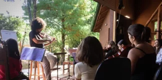 Crianças aprendendo a tocar violino durante oficina do Festival Multicultural na Guarda do Embaú.