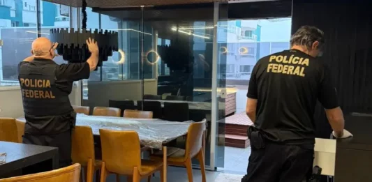 Policiais federais revistam imóvel durante operação contra tráfico internacional de pessoas.