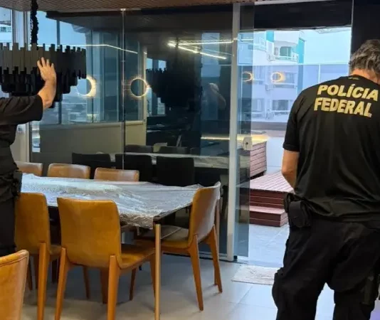 Policiais federais revistam imóvel durante operação contra tráfico internacional de pessoas.