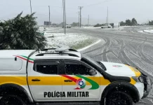 Viatura da Polícia Militar parada em um trevo na entrada de uma cidade da Serra Catarinense, com neve cobrindo o asfalto durante a Operação Estação Inverno.