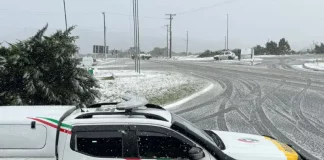 Viatura da Polícia Militar parada em um trevo na entrada de uma cidade da Serra Catarinense, com neve cobrindo o asfalto durante a Operação Estação Inverno.