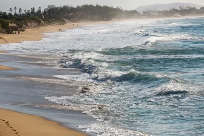 Mar agitado invadindo a faixa de areia da praia devido a ventos fortes no início da primavera em Santa Catarina.