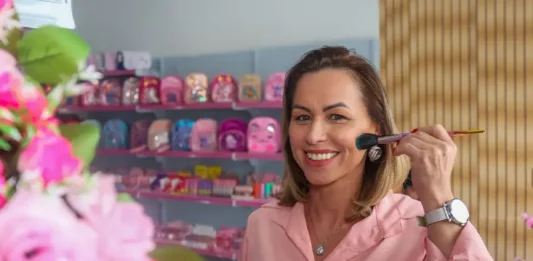 Empreendedora Lucirene Figueiredo em sua loja de maquiagens, exibindo o estoque ampliado com o crédito obtido pelo Programa Juro Zero.