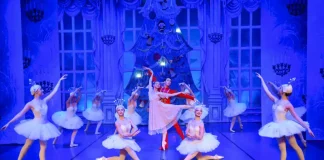 Bailarinos se apresentam no palco durante a encenação da peça O Quebra-Nozes, com figurinos coloridos e movimentos sincronizados que retratam a magia do balé natalino.