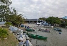Barcos de pesca atracados próximos ao Rancho de Pesca Hilário Vieira, na Beira-Mar de São José, com pescadores trabalhando nas redes.
