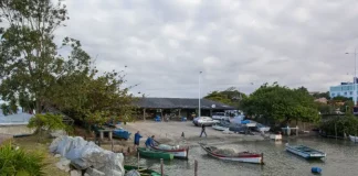 Barcos de pesca atracados próximos ao Rancho de Pesca Hilário Vieira, na Beira-Mar de São José, com pescadores trabalhando nas redes.