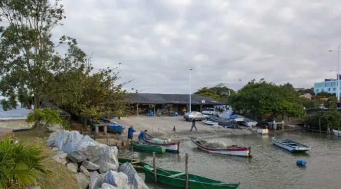 Barcos de pesca atracados próximos ao Rancho de Pesca Hilário Vieira, na Beira-Mar de São José, com pescadores trabalhando nas redes.