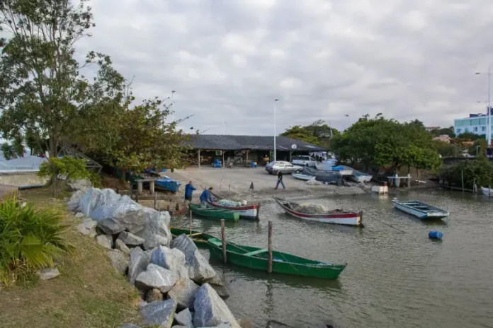 Barcos de pesca atracados próximos ao Rancho de Pesca Hilário Vieira, na Beira-Mar de São José, com pescadores trabalhando nas redes.