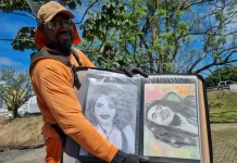 Luciano do Carmo de Paula, roçador de São José, com uniforme de trabalho, segurando uma pasta com seus desenhos artísticos.
