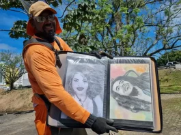 Luciano do Carmo de Paula, roçador de São José, com uniforme de trabalho, segurando uma pasta com seus desenhos artísticos.