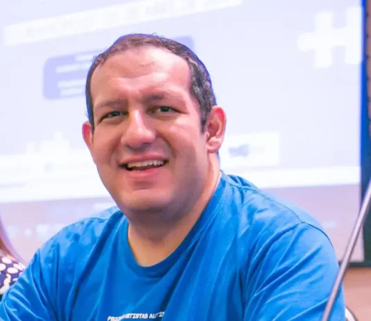 Cartunista catarinense lança livro sobre o autista no mercado de trabalho Cartunista Rodrigo Tramonte, vestindo camiseta azul com a estampa da capa de Humor Azul, posa ao lado do livro exposto, que aborda a experiência de autista no mercado de trabalho.