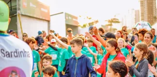 Crianças participam animadas, vestindo camisetas verdes e interagindo em grupo, representando a SouBio Run Kids, em Florianópolis, evento do Dia das Crianças.