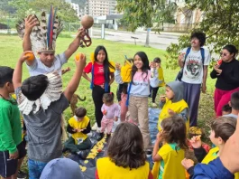 Estudantes e comunidade indígena compartilham um piquenique na agrofloresta, fortalecendo a troca de saberes tradicionais e práticas sustentáveis.