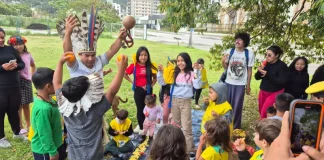 Estudantes e comunidade indígena compartilham um piquenique na agrofloresta, fortalecendo a troca de saberes tradicionais e práticas sustentáveis.