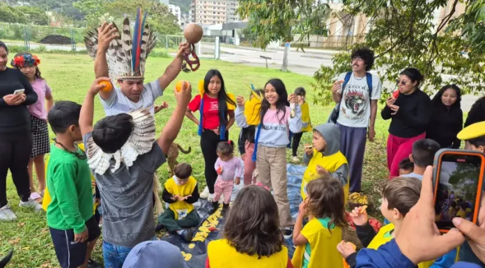 Estudantes e comunidade indígena compartilham um piquenique na agrofloresta, fortalecendo a troca de saberes tradicionais e práticas sustentáveis.