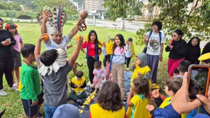 Estudantes e comunidade indígena compartilham um piquenique na agrofloresta, fortalecendo a troca de saberes tradicionais e práticas sustentáveis.