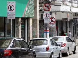 Carros estacionados nas vagas da Zona Azul em Florianópolis, com placas de sinalização ao fundo.