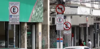 Carros estacionados nas vagas da Zona Azul em Florianópolis, com placas de sinalização ao fundo.