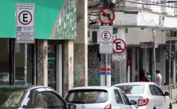 Carros estacionados nas vagas da Zona Azul em Florianópolis, com placas de sinalização ao fundo.