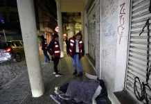 Agentes da Prefeitura de Florianópolis, com colete laranja, abordam pessoas em situação de rua para avaliação e possível encaminhamento a internações involuntárias.