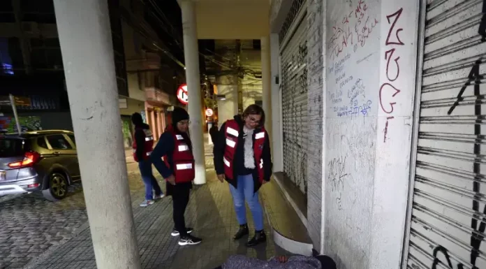 Florianópolis inicia novo modelo para ampliar internações involuntárias Agentes da Prefeitura de Florianópolis, com colete laranja, abordam pessoas em situação de rua para avaliação e possível encaminhamento a internações involuntárias.
