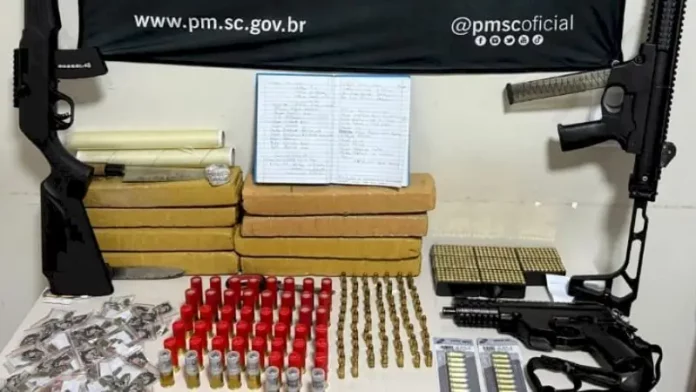 Armas e drogas apreendidas durante operação da Polícia Militar no Norte da Ilha, incluindo espingardas, munições e pacotes de substâncias entorpecentes.