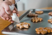 Mãos de uma mulher confeitando biscoitos, ilustrando o curso gratuito de fabricação de biscoitos oferecido pela Prefeitura de Biguaçu em parceria com o SENAI.