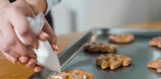 Mãos de uma mulher confeitando biscoitos, ilustrando o curso gratuito de fabricação de biscoitos oferecido pela Prefeitura de Biguaçu em parceria com o SENAI.