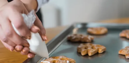 Mãos de uma mulher confeitando biscoitos, ilustrando o curso gratuito de fabricação de biscoitos oferecido pela Prefeitura de Biguaçu em parceria com o SENAI.