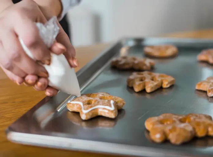 Mãos de uma mulher confeitando biscoitos, ilustrando o curso gratuito de fabricação de biscoitos oferecido pela Prefeitura de Biguaçu em parceria com o SENAI.