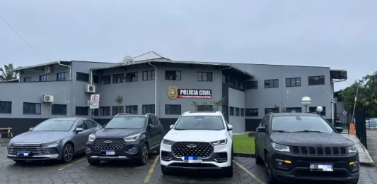 Quatro carros de luxo apreendidos na Operação Falso Samaritano estão estacionados em frente à delegacia de polícia