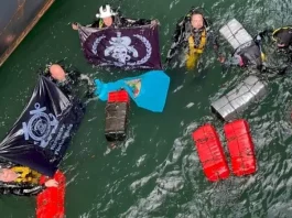 Mergulhadores táticos da Polícia Federal recolhendo pacotes de cocaína escondidos no casco submerso de navio no porto de Imbituba.