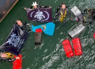 Mergulhadores táticos da Polícia Federal recolhendo pacotes de cocaína escondidos no casco submerso de navio no porto de Imbituba.