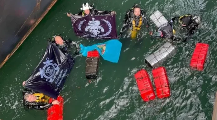 Mergulhadores táticos da Polícia Federal recolhendo pacotes de cocaína escondidos no casco submerso de navio no porto de Imbituba.