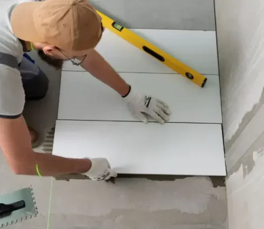 Profissional aplicando piso em obra, representando a qualificação profissional oferecida nos cursos gratuitos de São José.