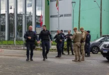Guardas municipais e policiais militares em frente a comércio durante a Operação Fio Desencapado contra furto de fios de iluminação em São José.