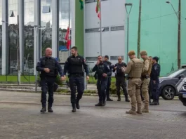 Guardas municipais e policiais militares em frente a comércio durante a Operação Fio Desencapado contra furto de fios de iluminação em São José.