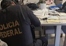 Agente da Polícia Federal analisando documentos durante cumprimento de mandado de busca na Operação Alea, em Santa Catarina.