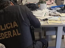 Agente da Polícia Federal analisando documentos durante cumprimento de mandado de busca na Operação Alea, em Santa Catarina.