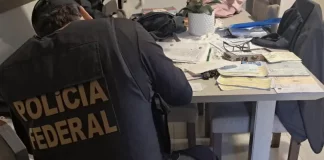 Agente da Polícia Federal analisando documentos durante cumprimento de mandado de busca na Operação Alea, em Santa Catarina.