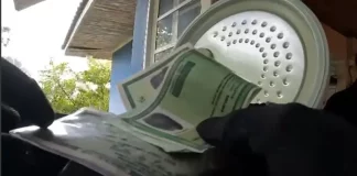 Mãos de policial federal segurando documentos apreendidos durante operação que investiga fraude bancária.