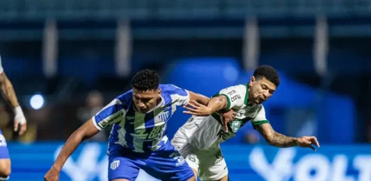 Jogador do Avaí e do Coritiba disputam a bola em campo, representando a intensidade e a rivalidade do duelo pelo Brasileirão.