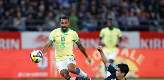 O futebol que encanta e decepciona: o retrato de uma paixão nacional Jogador da seleção brasileira tenta avançar com a bola enquanto é desarmado por um defensor da seleção japonesa durante uma partida de futebol. A imagem ilustra o confronto entre Brasil e Japão, usada para representar o tema do desempenho da seleção brasileira.