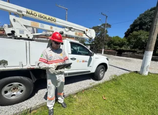 Funcionário da Celesc utilizando tablet em frente a veículo de atendimento emergencial, ilustrando o uso da internet Starlink para agilizar operações em campo.